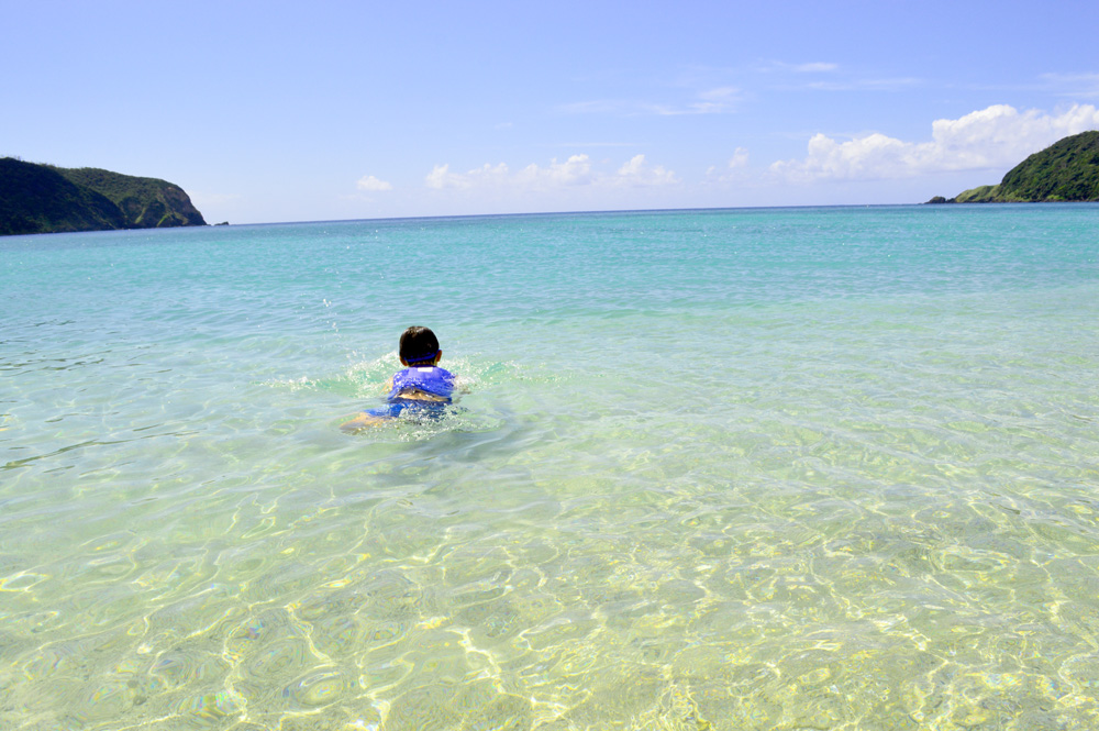 国直海岸の青い海で泳ぐ子供