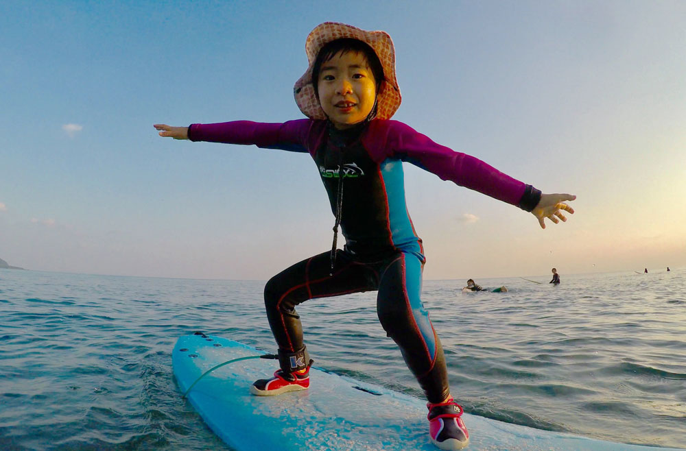 奄美でサーフィン体験する子ども：GREENHILL