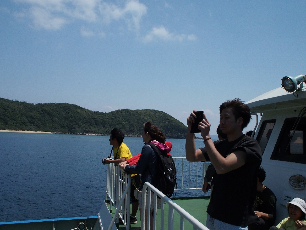 与路島に向かう船で写真を撮る男性