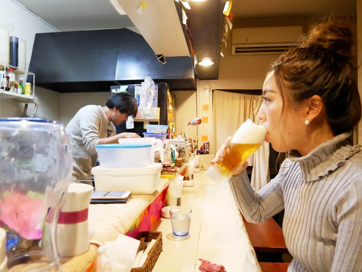 カウンター席で生ビールを飲む女性の横顔