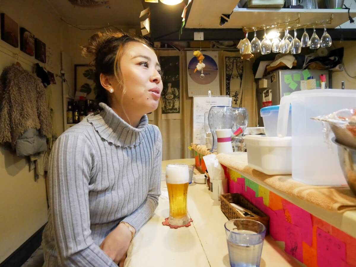カウンターで生ビールを飲む女性